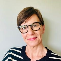 Woman with short brown hair, wearing glasses and striped sweater, smiling.