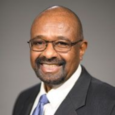 Woman with blonde hair, smiling, wearing a red tank top, against a dark background.