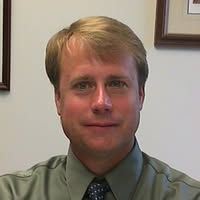 Man with blond hair, wearing a green shirt, looking at the camera.