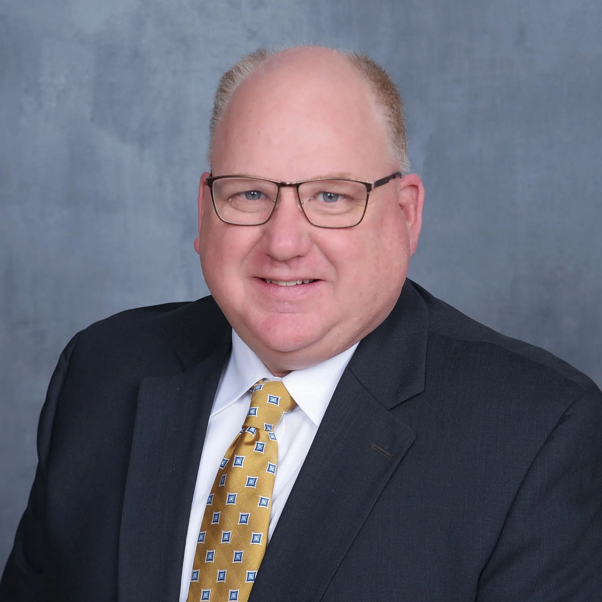Rotary Club meeting; people seated at tables, speaker at podium showing a slide, American flag in background.
