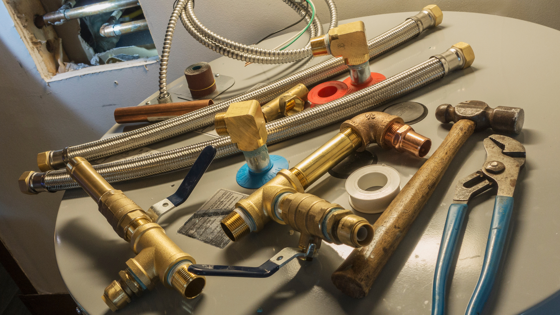 A bunch of plumbing tools are sitting on top of a water heater.