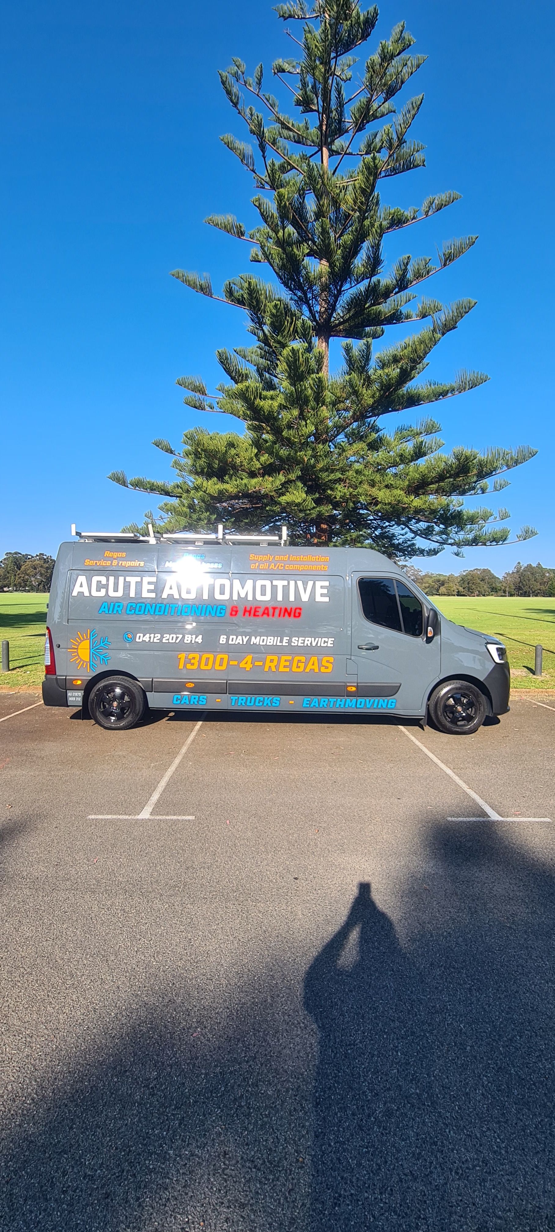 A van is parked in a parking lot next to a tree.
