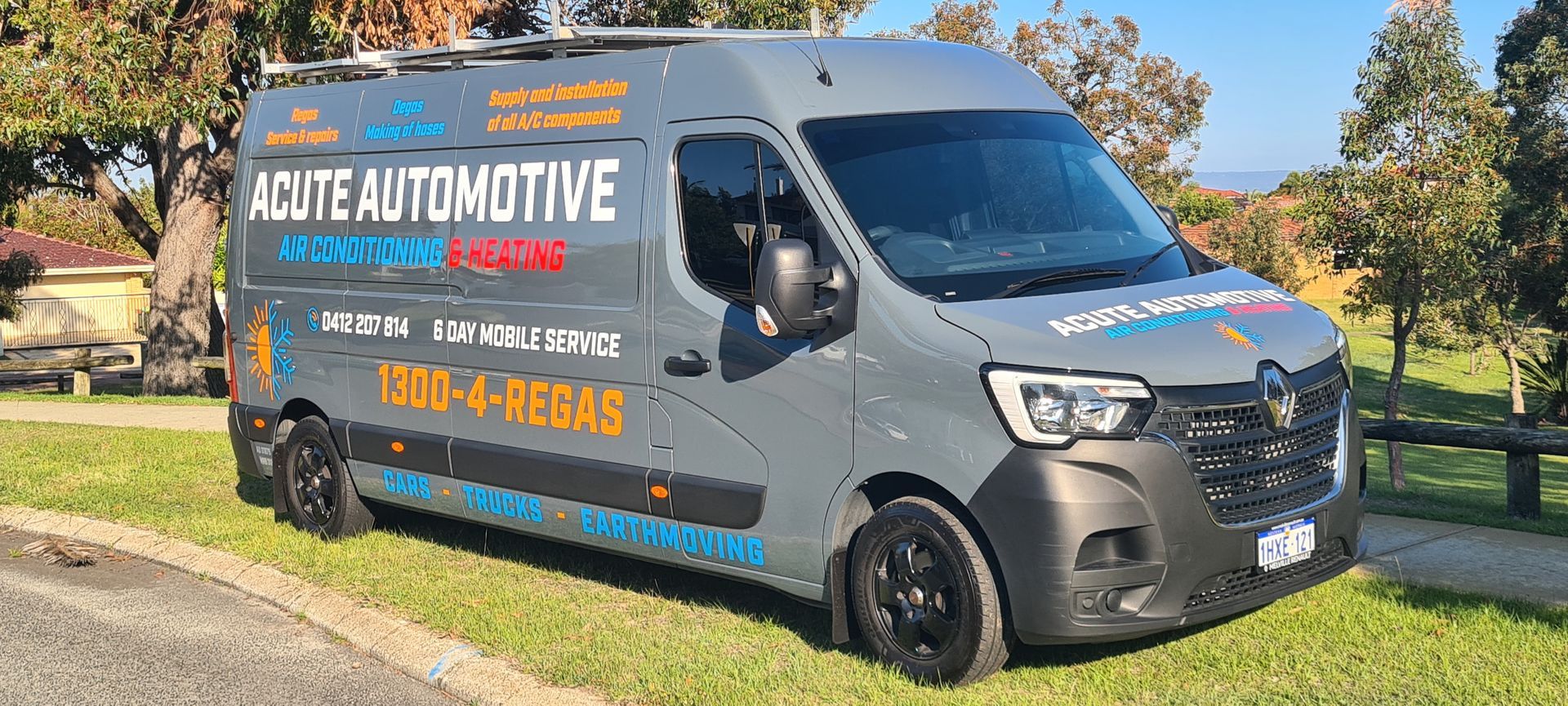A gray van is parked in the grass on the side of the road.