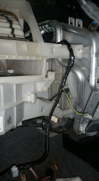 A close up of a car air conditioner with wires coming out of it.