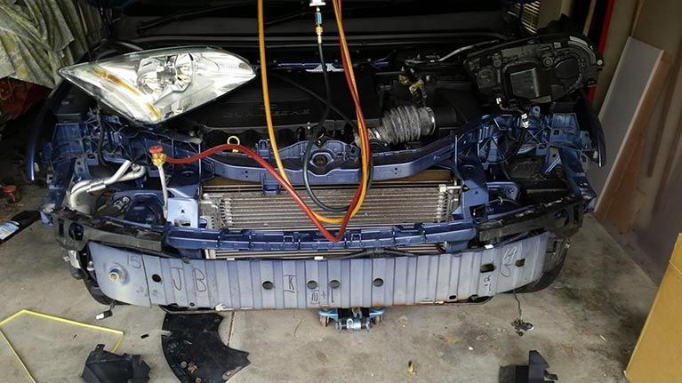 A blue car is being worked on in a garage.
