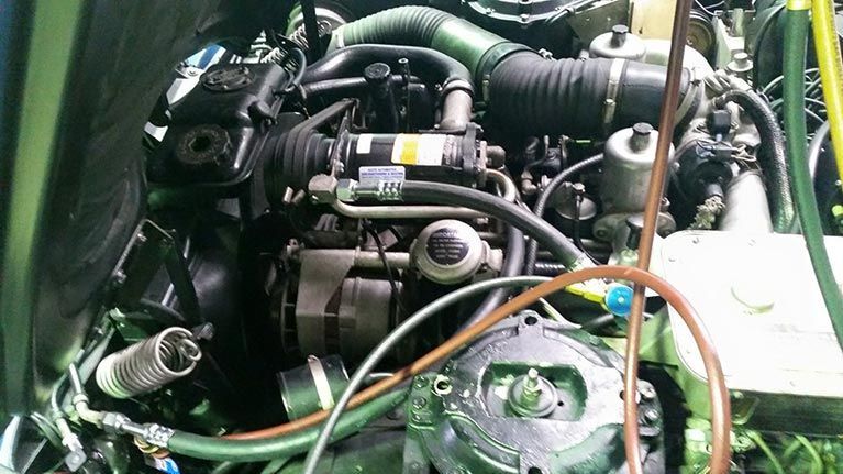 A close up of a green engine with a bunch of wires coming out of it