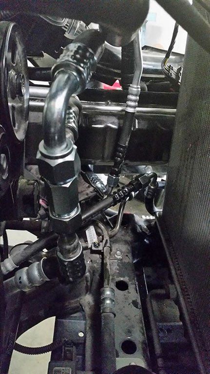 A close up of a hose attached to a car engine.