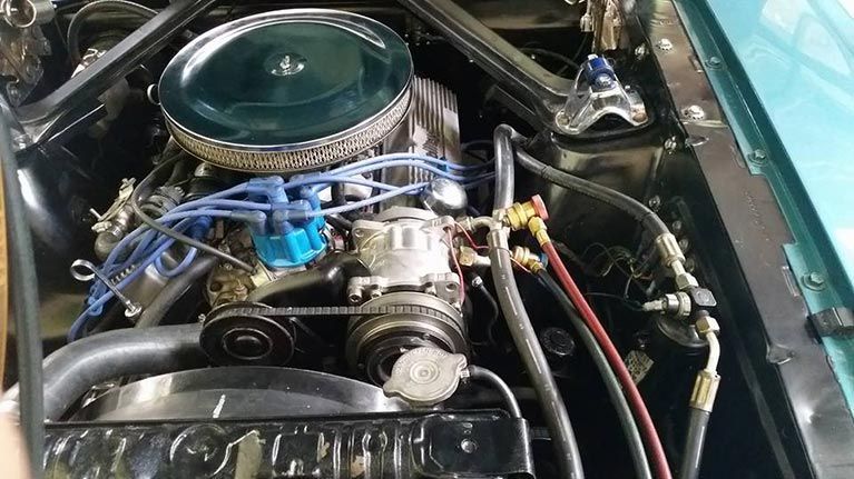 A close up of a car engine with a hood open.