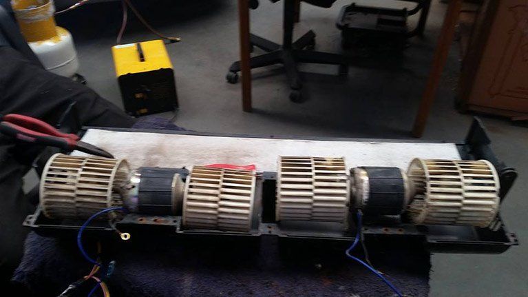 A person is working on a fan with a pair of pliers.