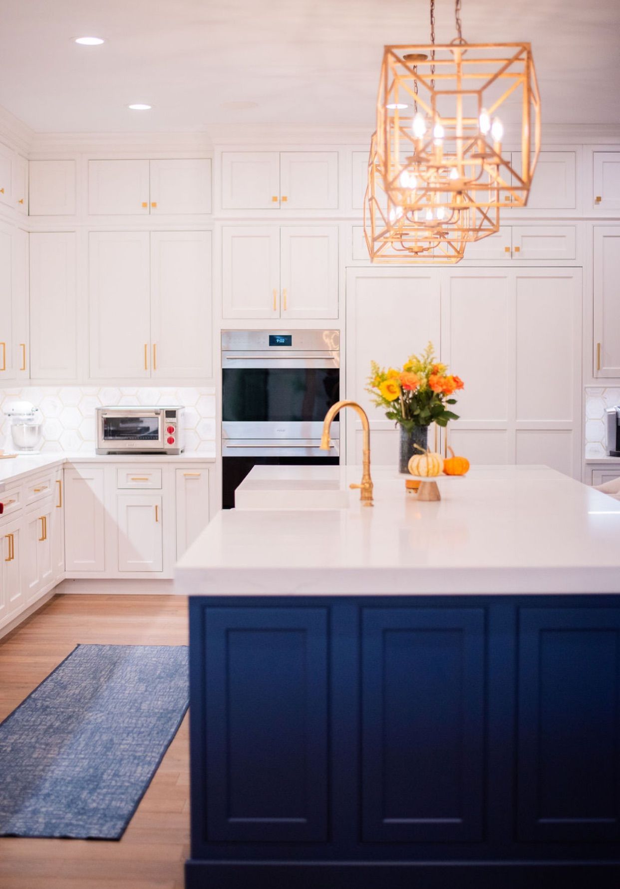 A kitchen with white cabinets and a blue island.