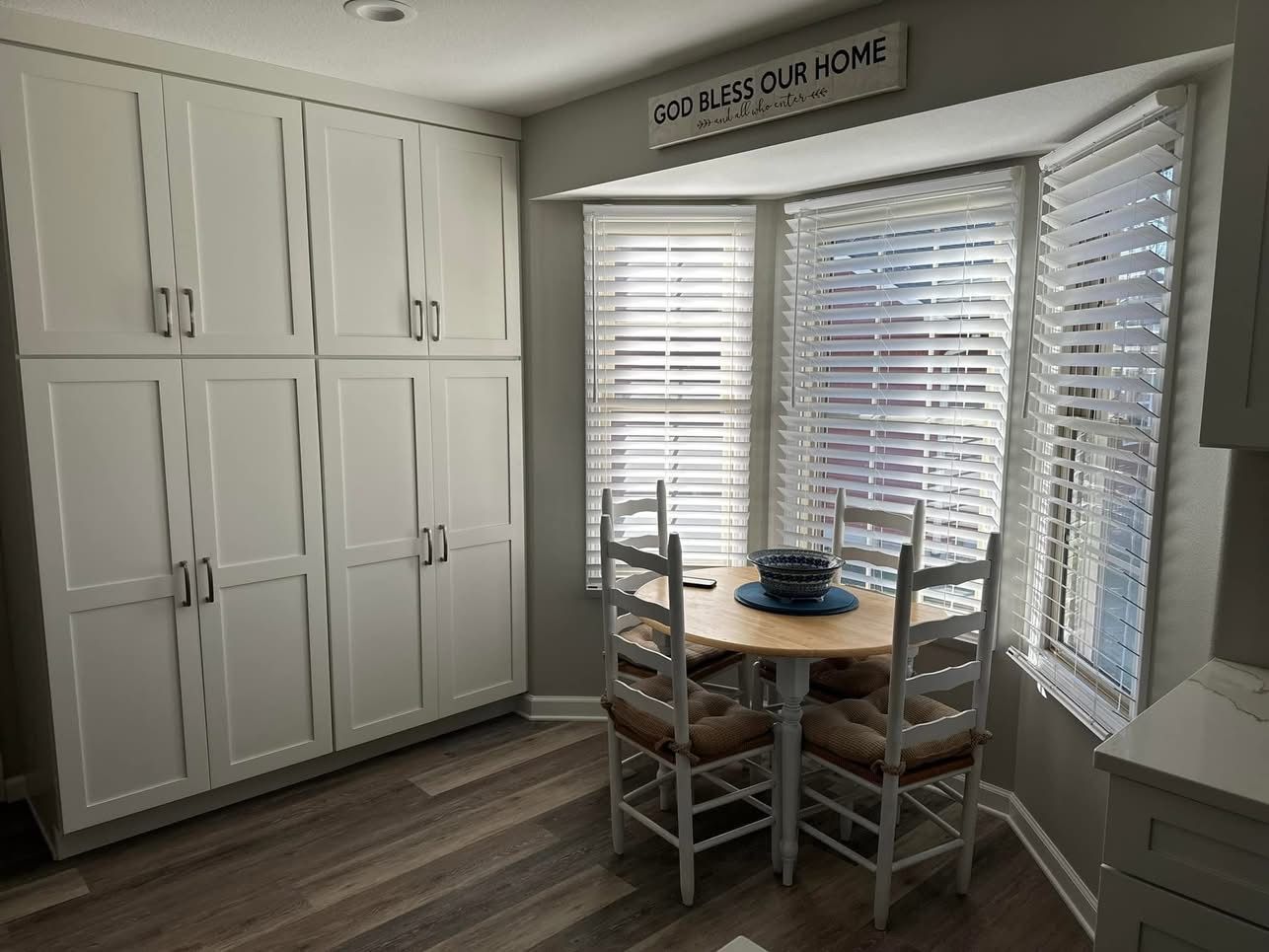 A dining room with a table and chairs in front of a bay window.