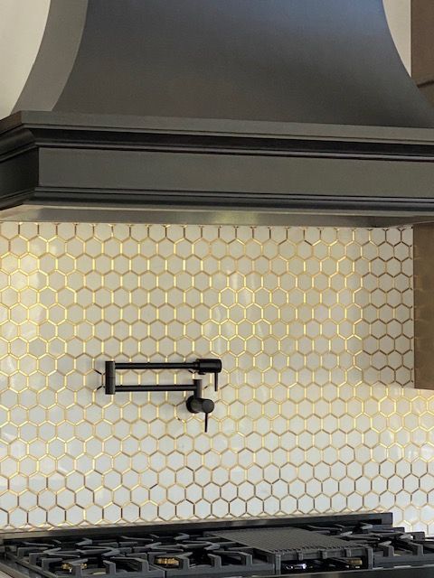 A kitchen with a stove top oven and a black hood.