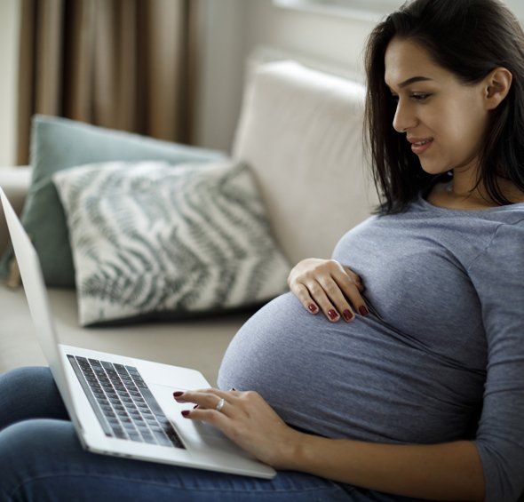 Pregnant Woman Browsing on Her Laptop — Arlington, TX — Omega Ob-Gyn Associates
