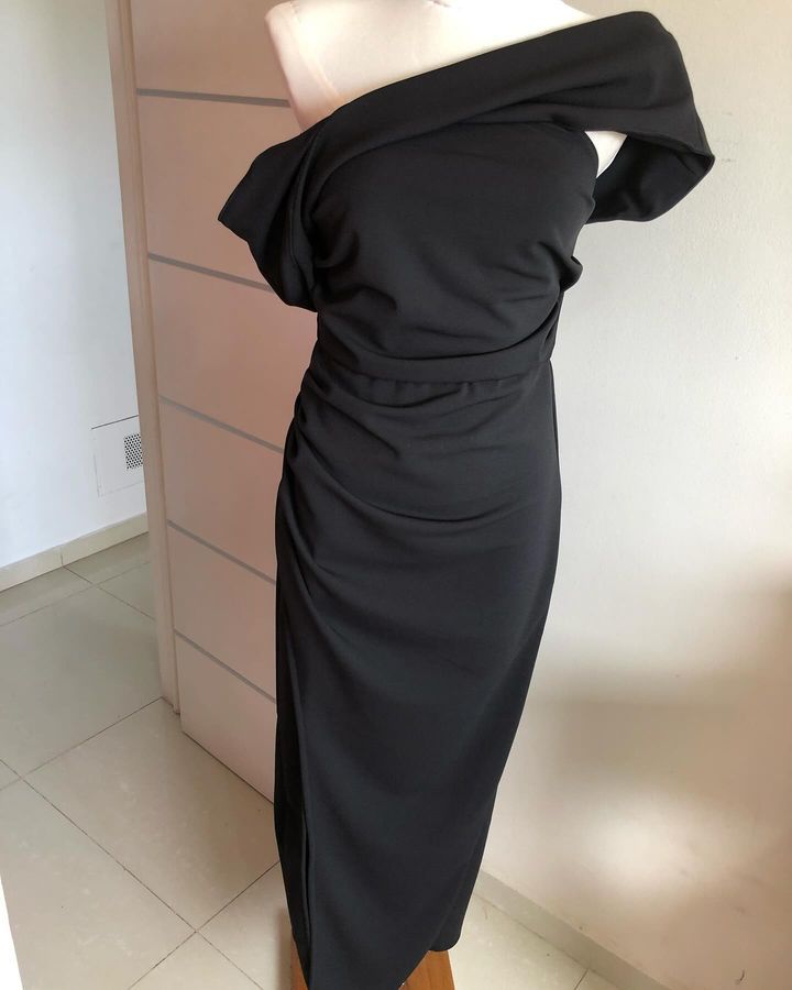 Un vestido negro con hombros descubiertos está sobre un maniquí.