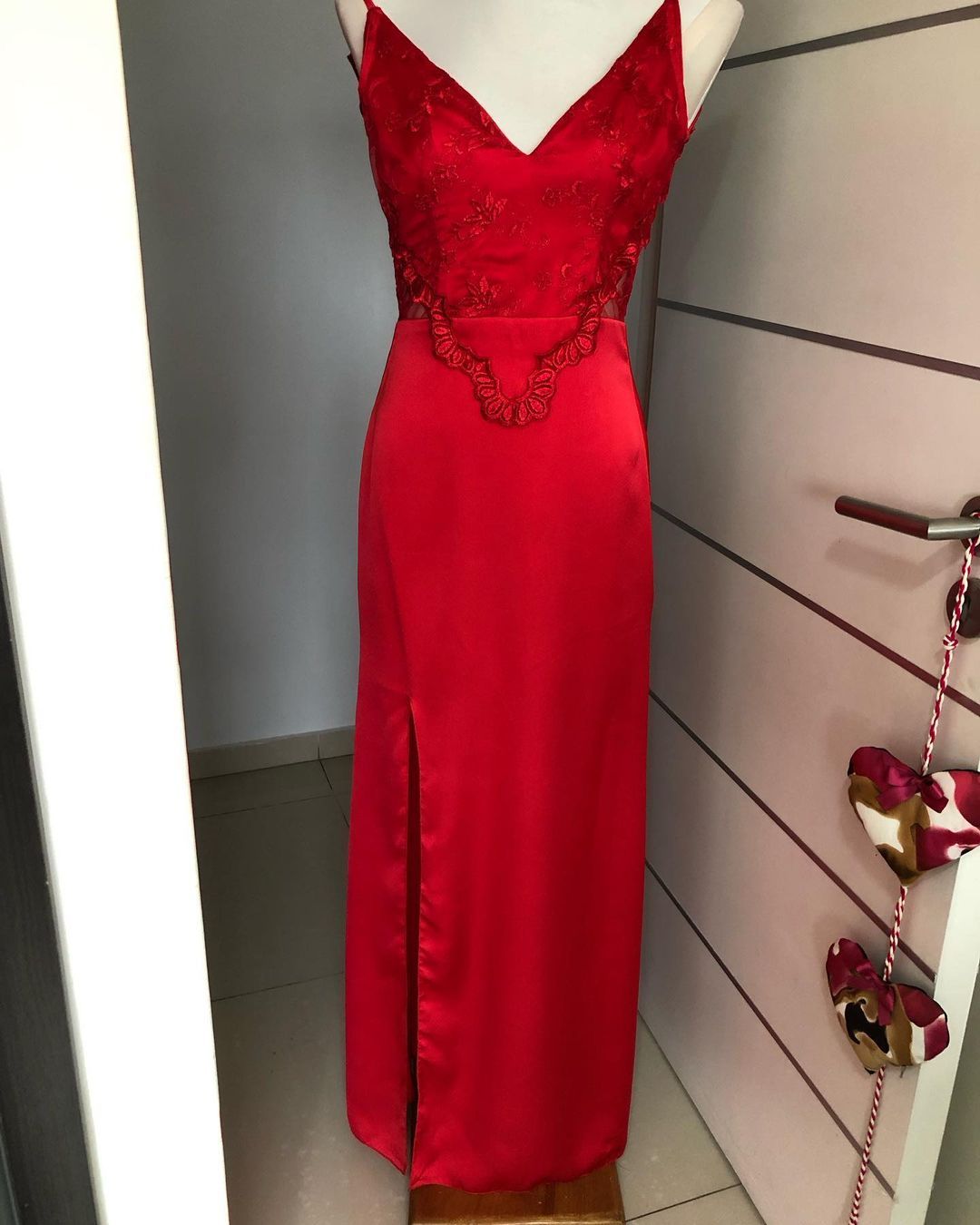 Un vestido rojo está sobre un maniquí frente a una puerta.