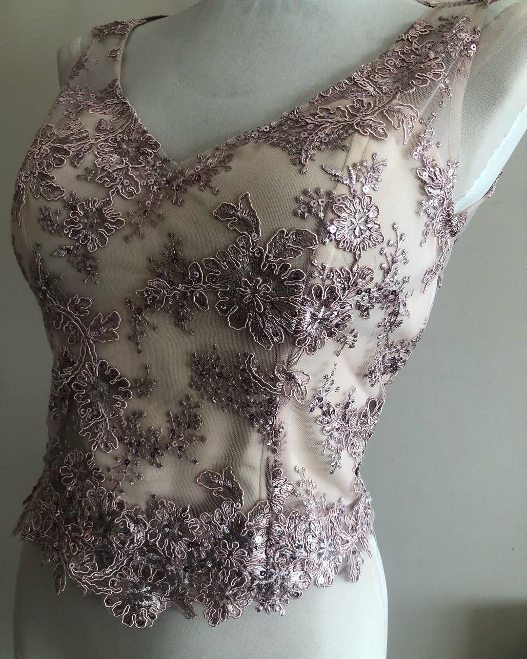 Una mujer lleva un top de encaje rosa sobre un maniquí.