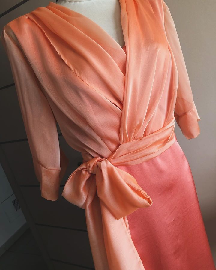Un maniquí lleva un vestido rosa con un lazo alrededor de la cintura.