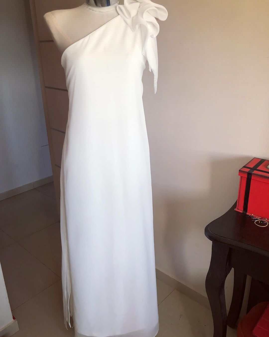 Un vestido blanco de un solo hombro está sobre un maniquí.