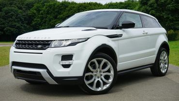 A white range rover is parked on the side of the road