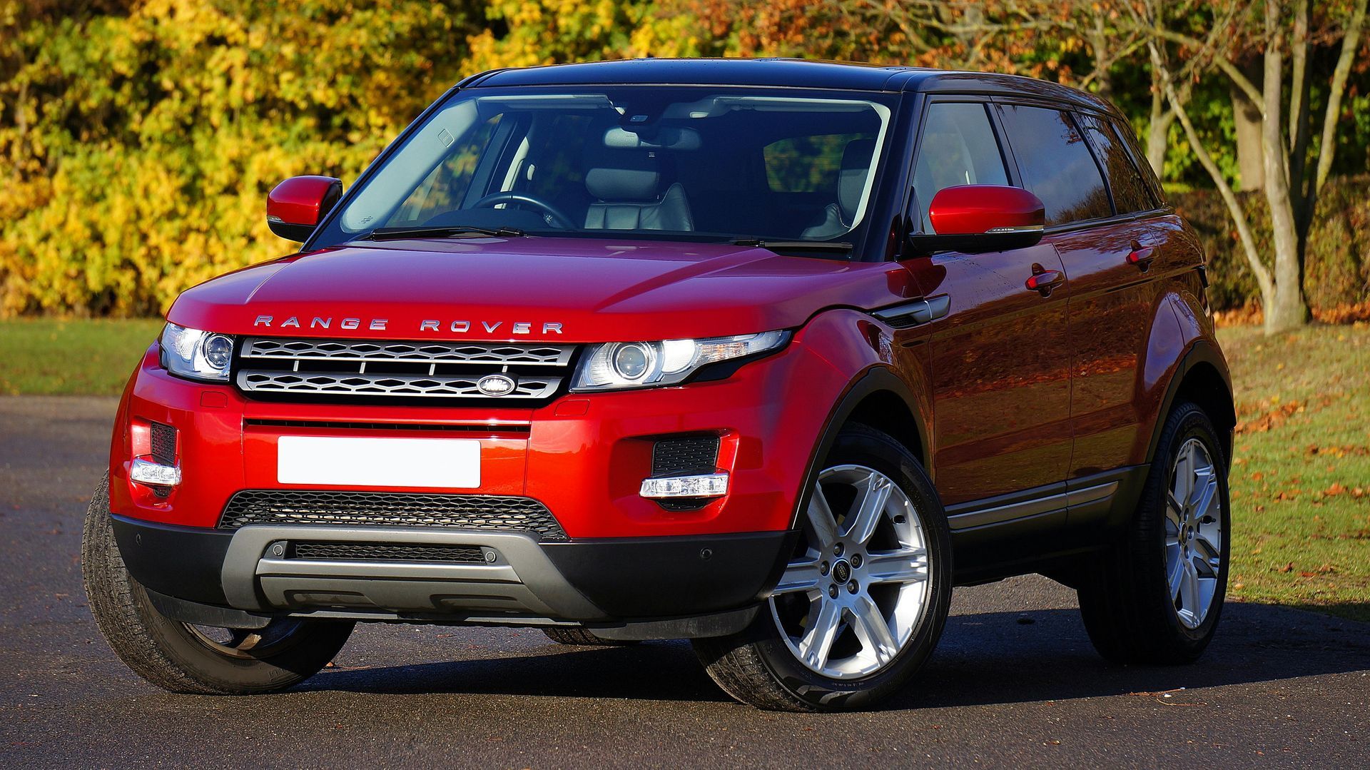 A red range rover is parked on the side of the road