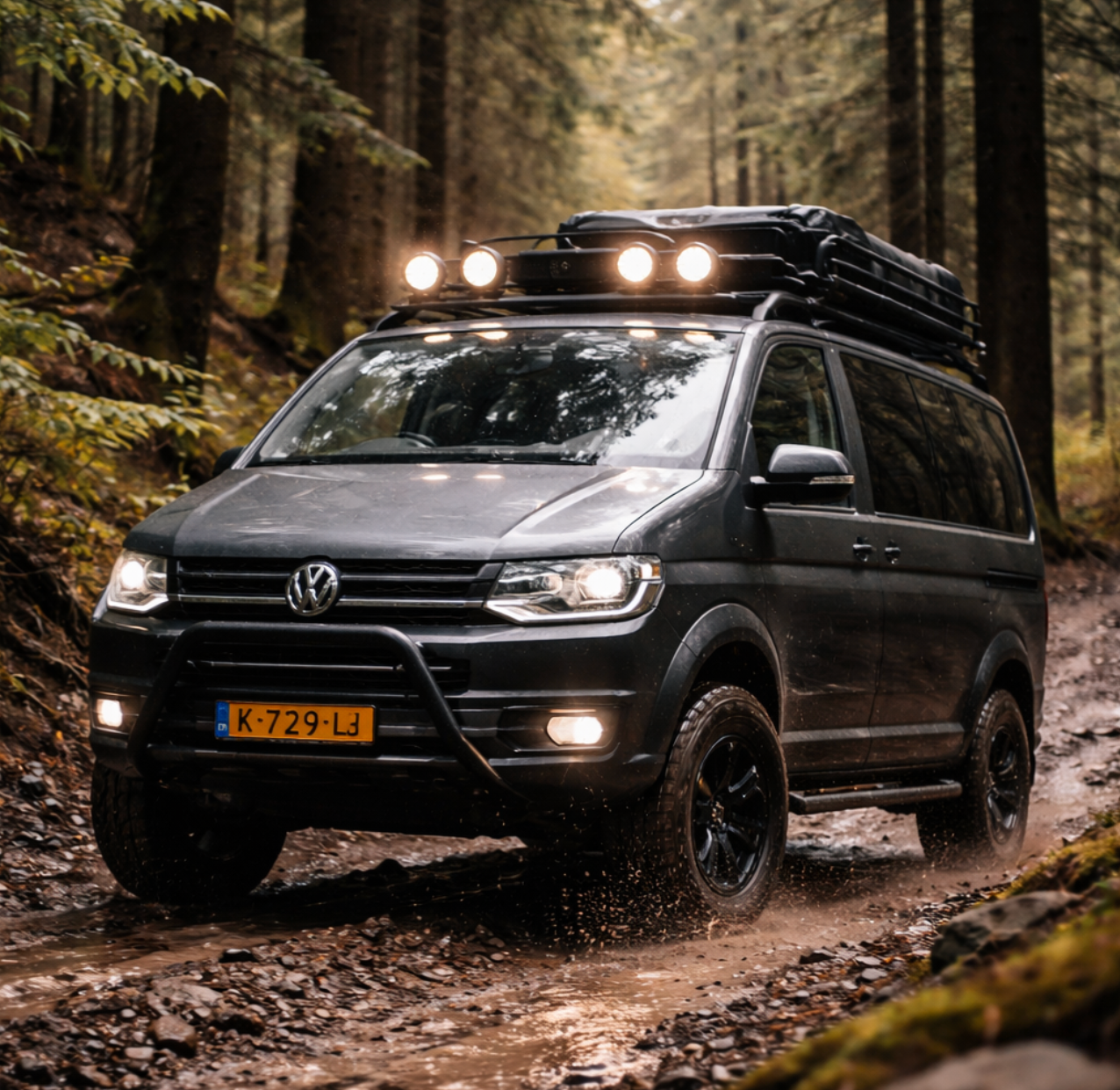 Donkergrijze Volkswagen terreinwagen met imperiaal en verlichting rijdt over een modderig bospad.