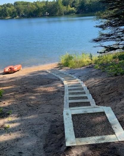 A staircase leading to a lake with a kayak in the background.