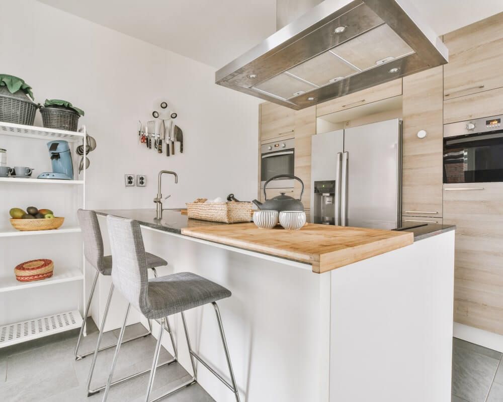 Modern kitchen with white island, stainless steel appliances, and wood accents.