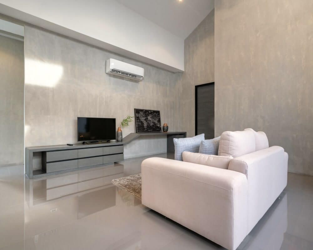 Modern living room with light gray walls, couch, TV, and polished floor.