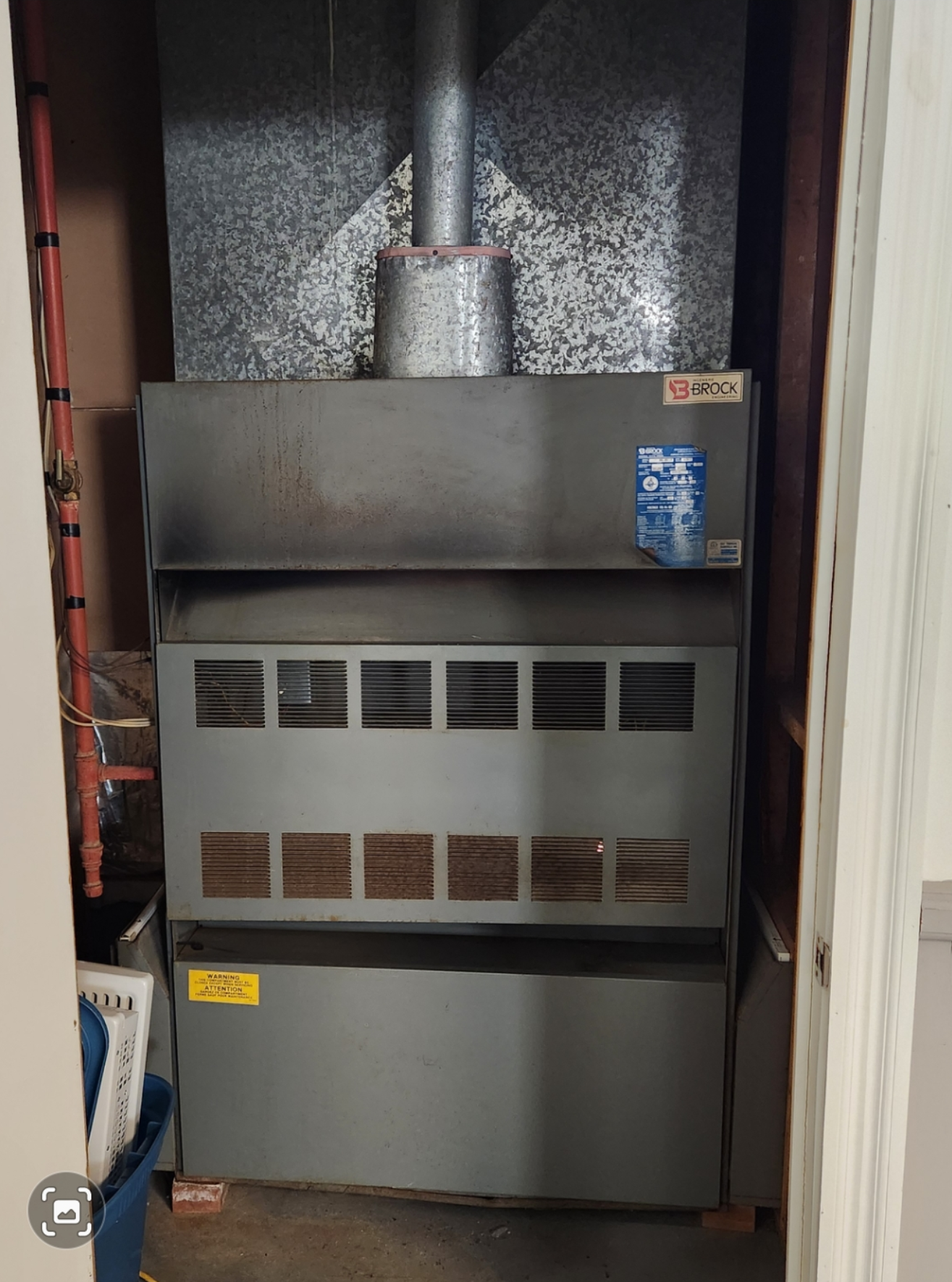 Un radiateur gris se trouve dans un placard à côté d'une porte.