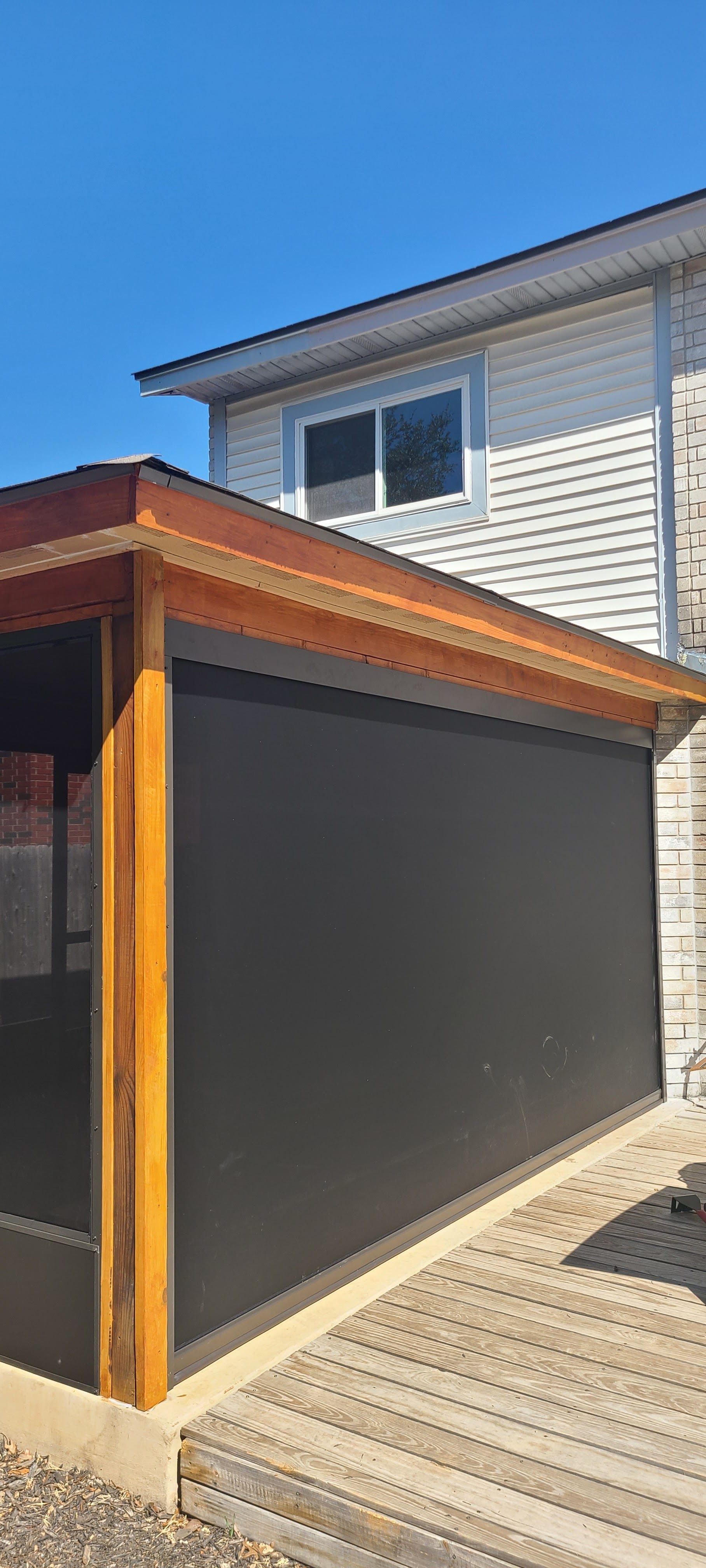 A view from inside a building through large windows at a silver pickup truck and a small trailer parked in a dry field.