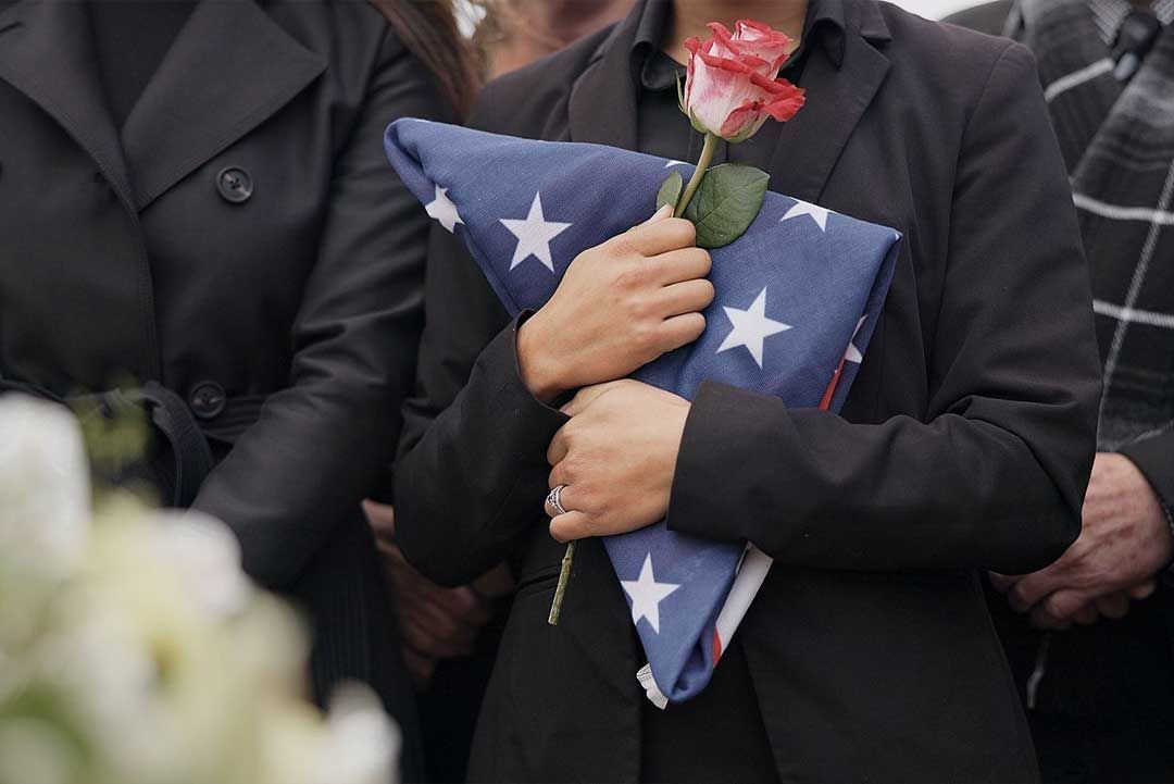 a little girl hugging a soldier with an american flag on his back
