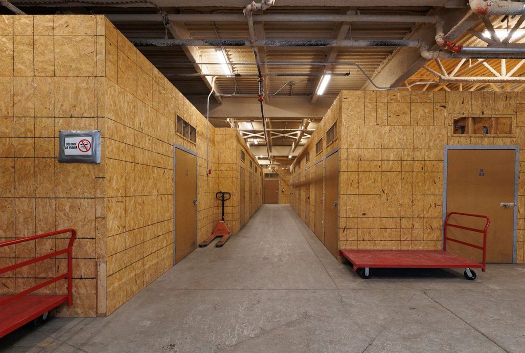 Long couloir aux murs, portes et chariots utilitaires en contreplaqué.