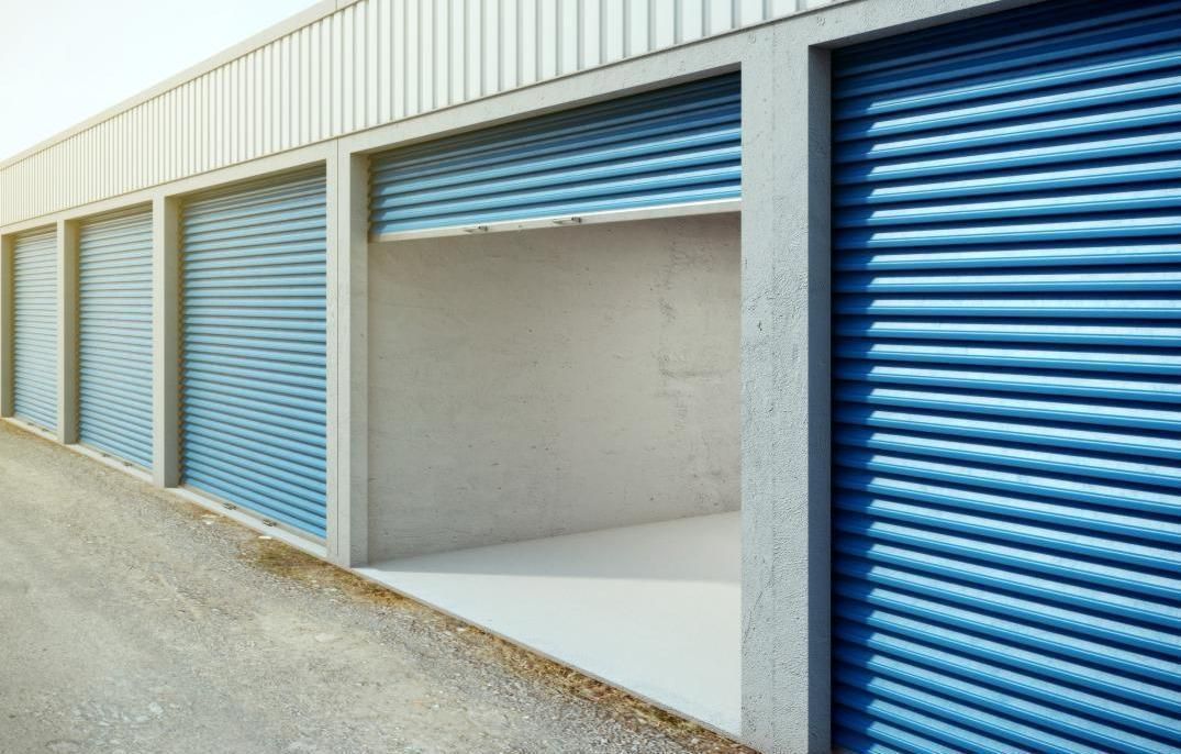 Portes bleues d'un box de stockage, une ouverte, le long d'un bâtiment.