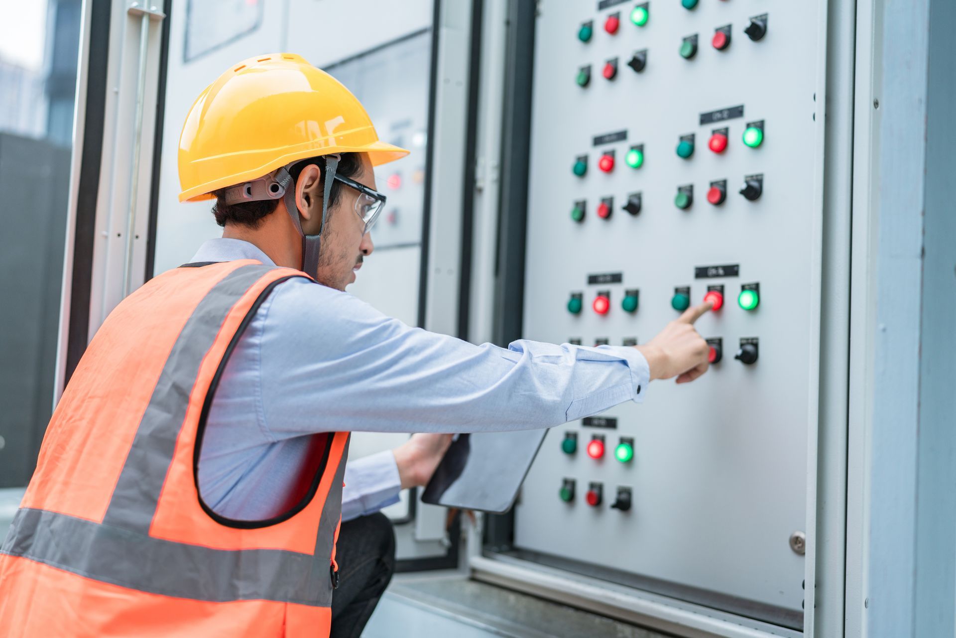 A focused technician in protective gear adjusts the controls on a gas mining electrical control syst