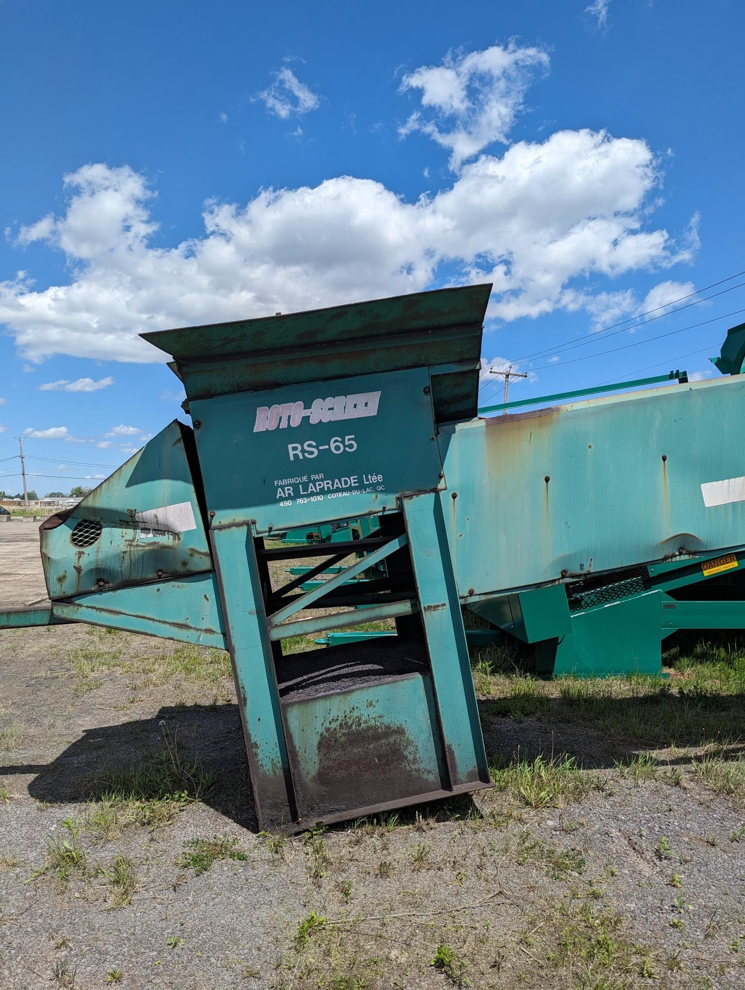 Une machine verte est assise au sommet d'un champ de terre.