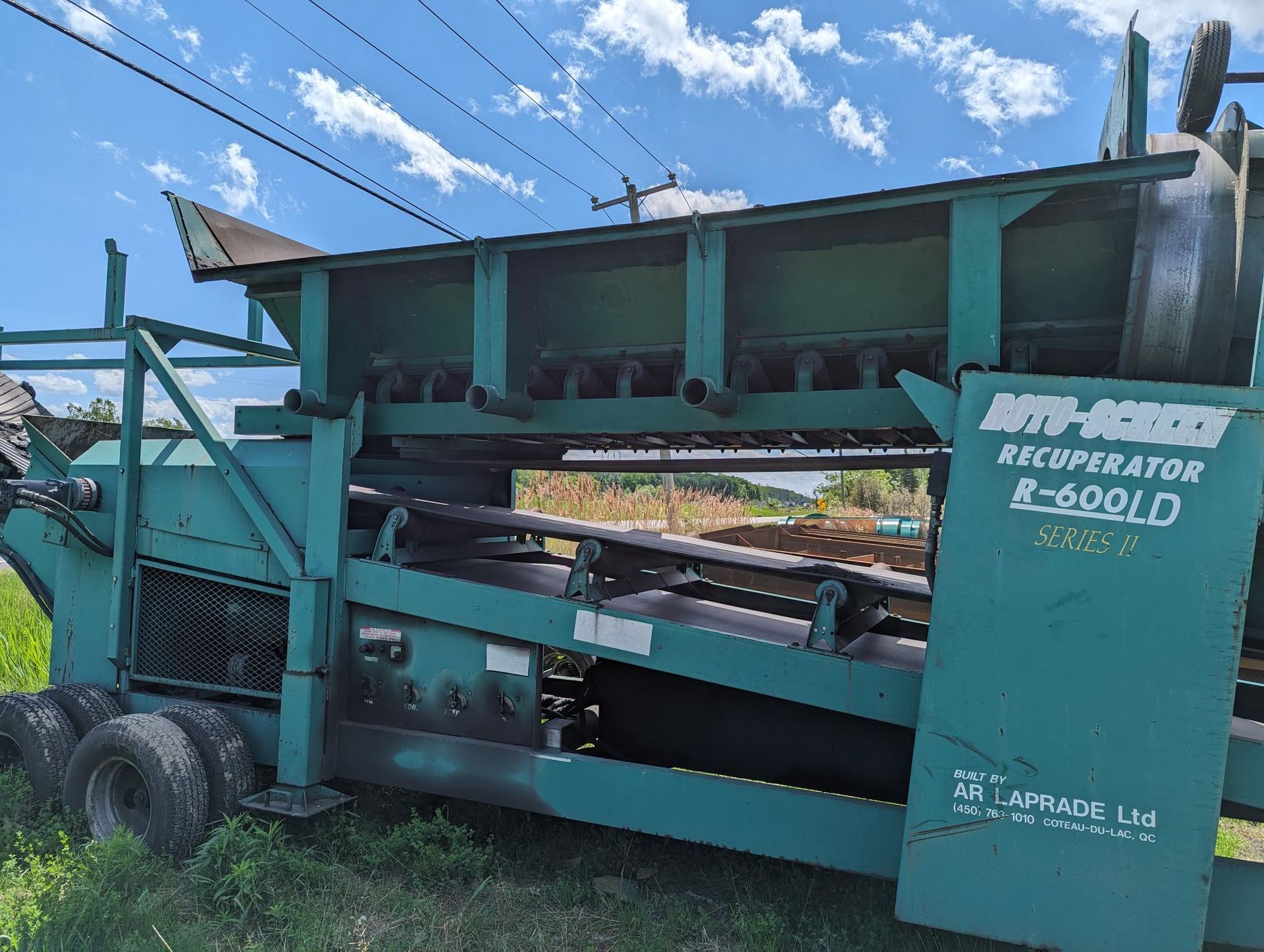 Une machine verte est garée dans un champ herbeux.