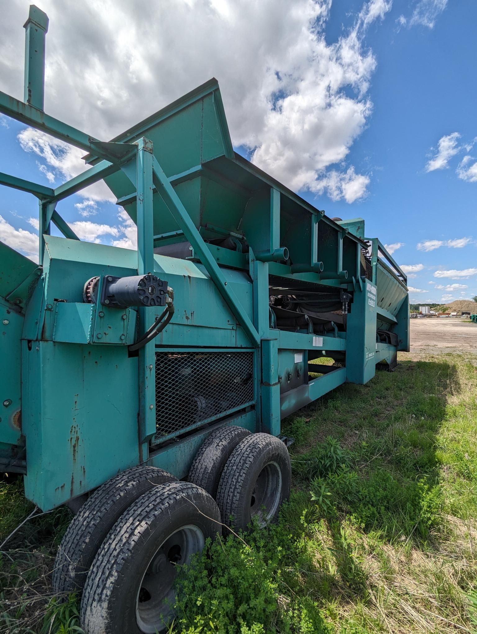 Une machine verte est assise au milieu d'un champ herbeux.