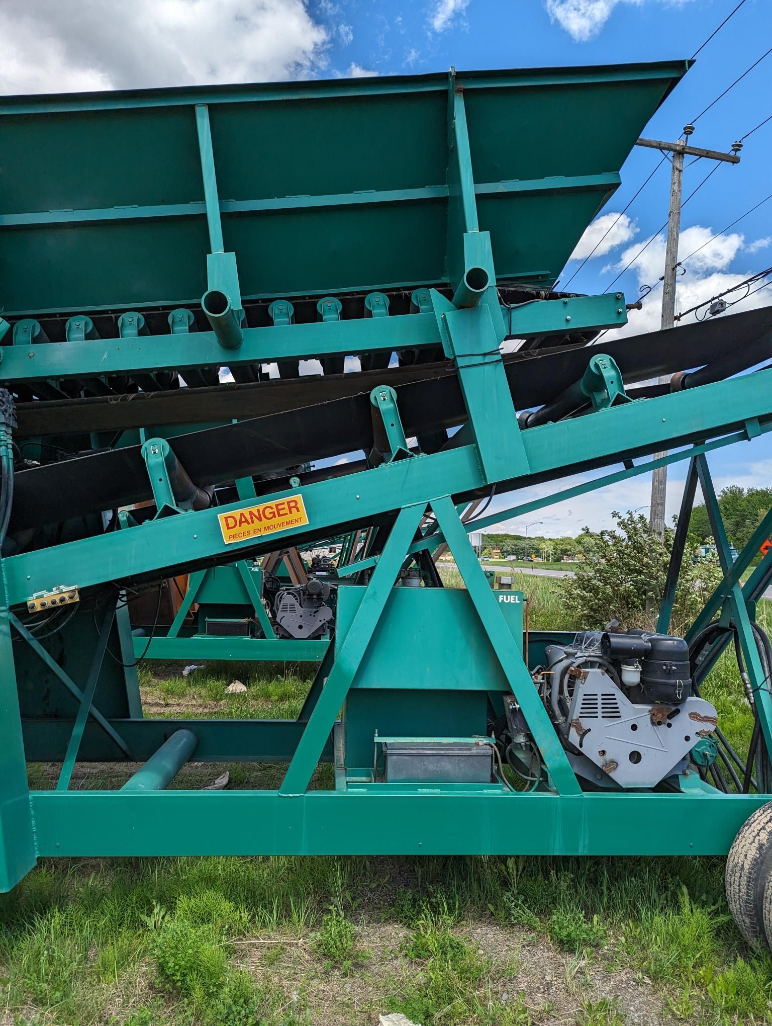 Une machine verte est garée dans un champ herbeux.