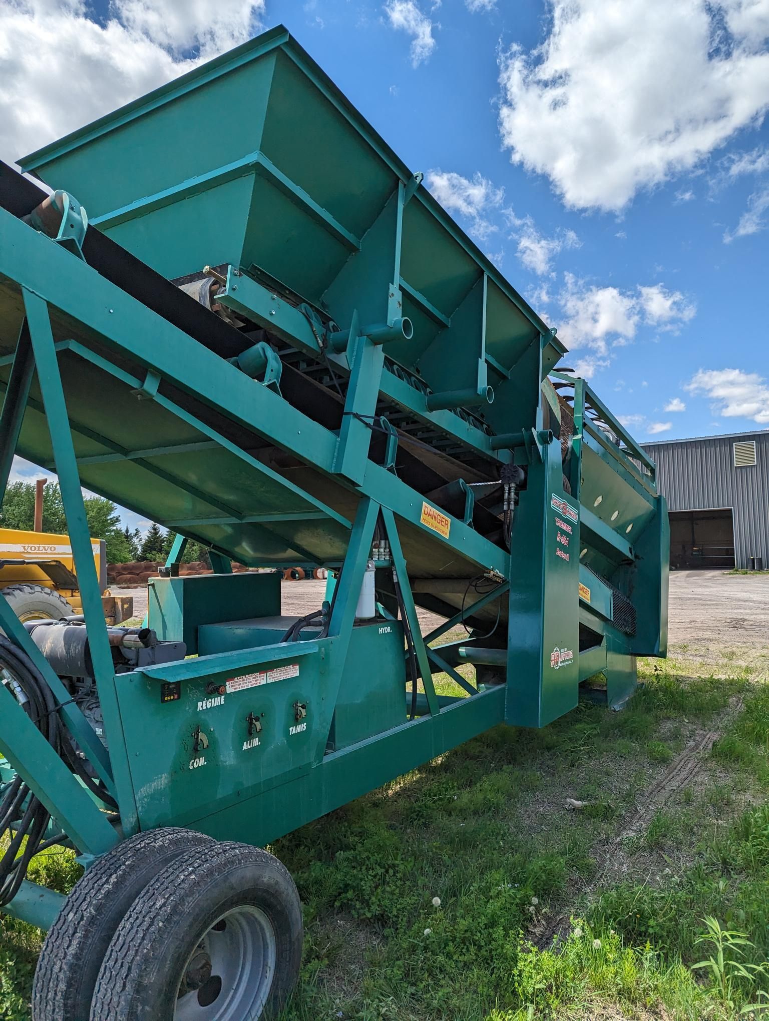 Une machine verte est garée dans l'herbe devant un immeuble.