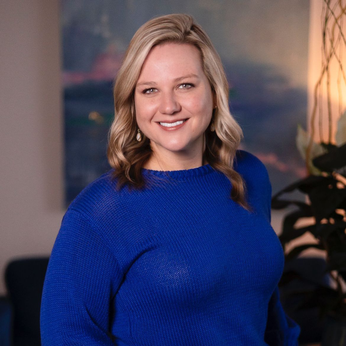 A woman in a blue sweater is smiling for the camera.