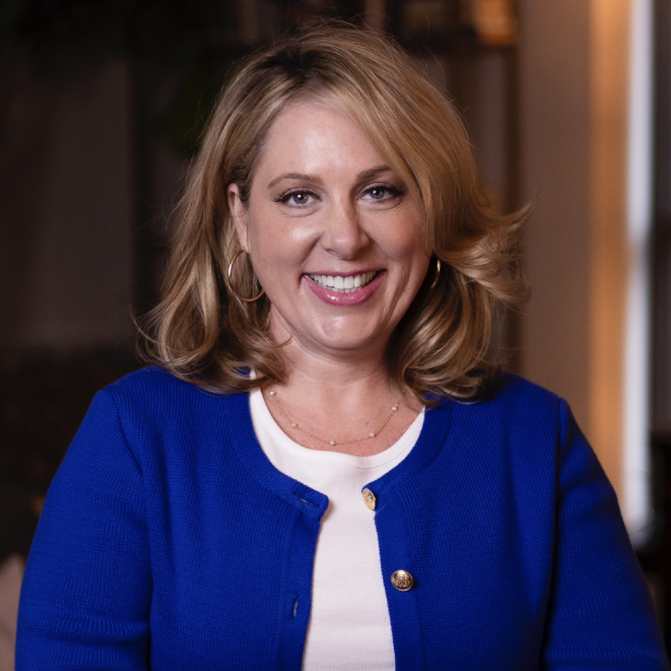 A woman is wearing a blue jacket and smiling for the camera.