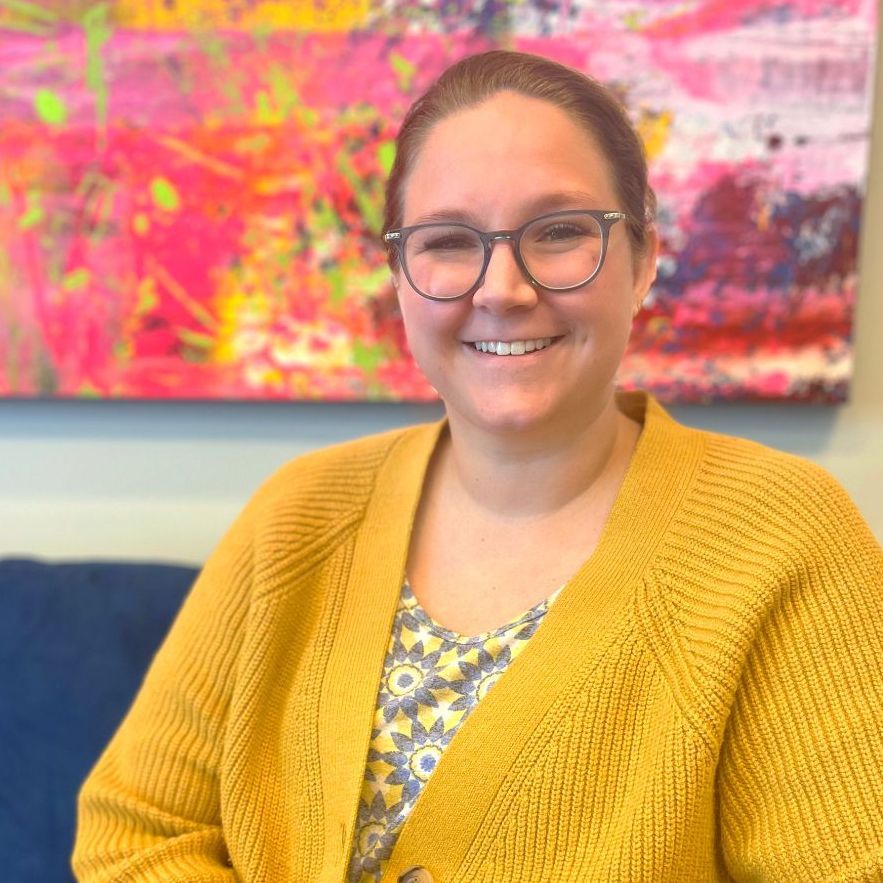 A woman in a pink sweater is smiling for the camera.