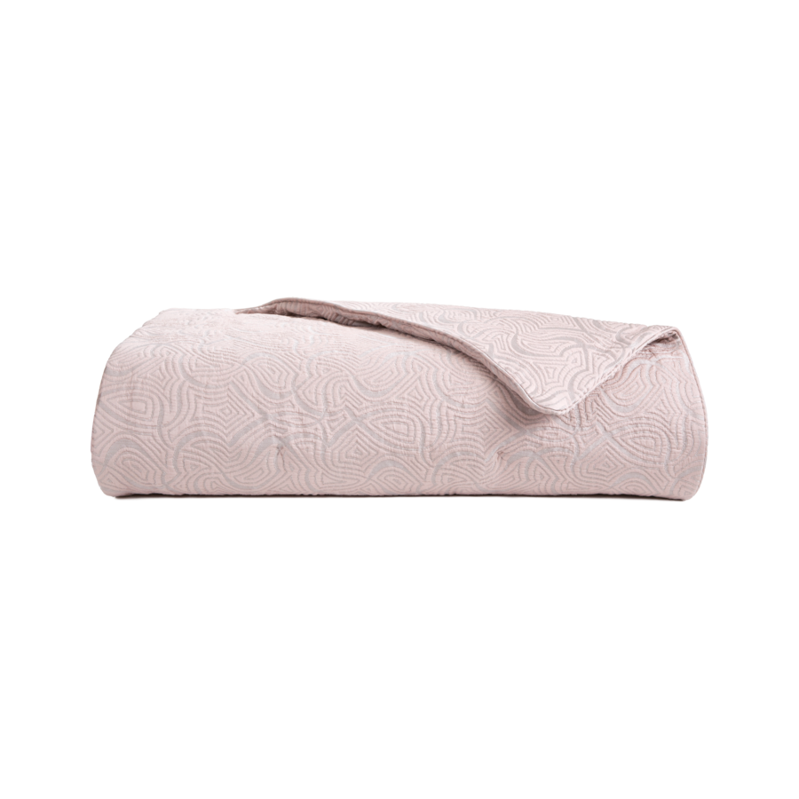Couverture matelassée rose clair pliée.
