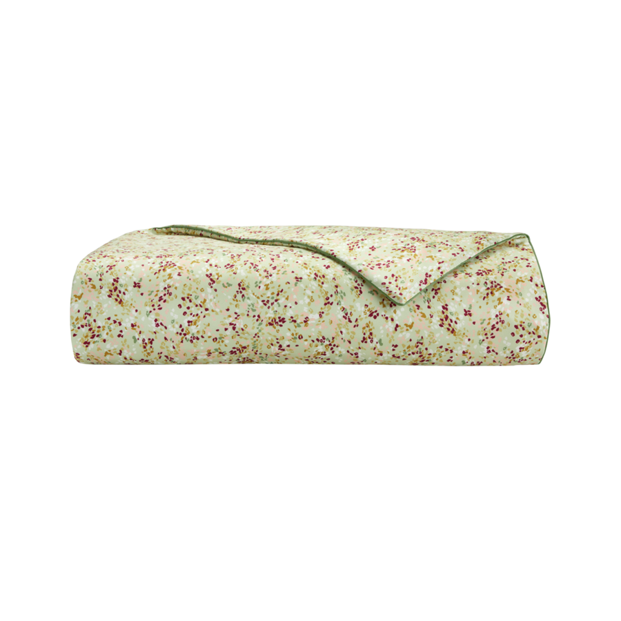 Un plaid plié, vert clair, orné d'un petit motif floral multicolore.