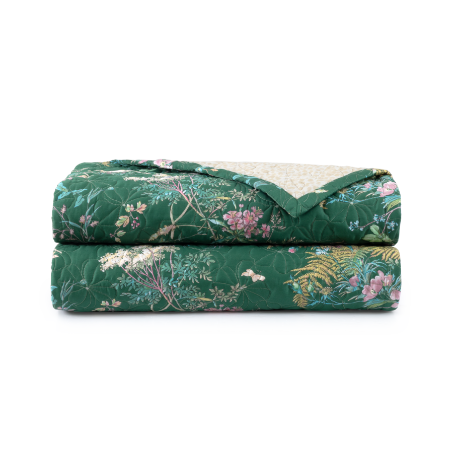 Deux couvertures matelassées vertes à motifs floraux, pliées et empilées l'une sur l'autre.
