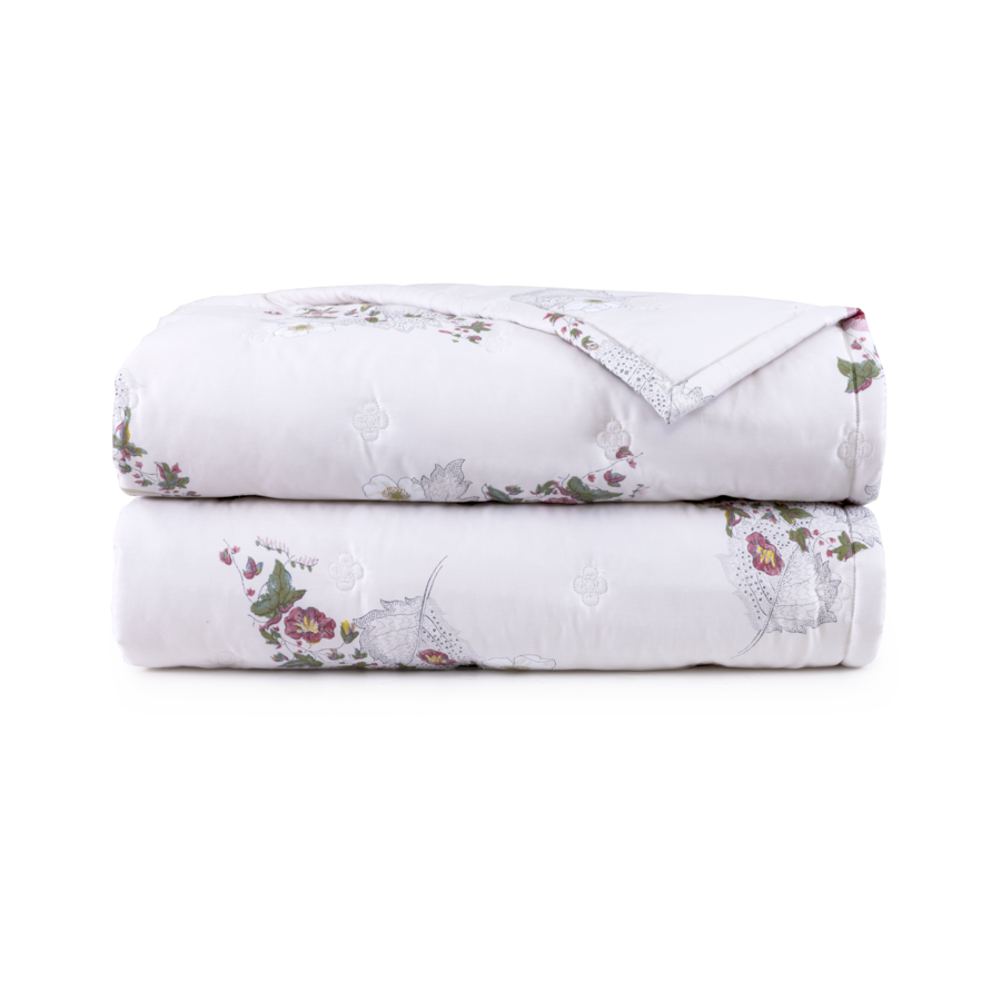 Deux courtepointes blanches pliées à motifs floraux.