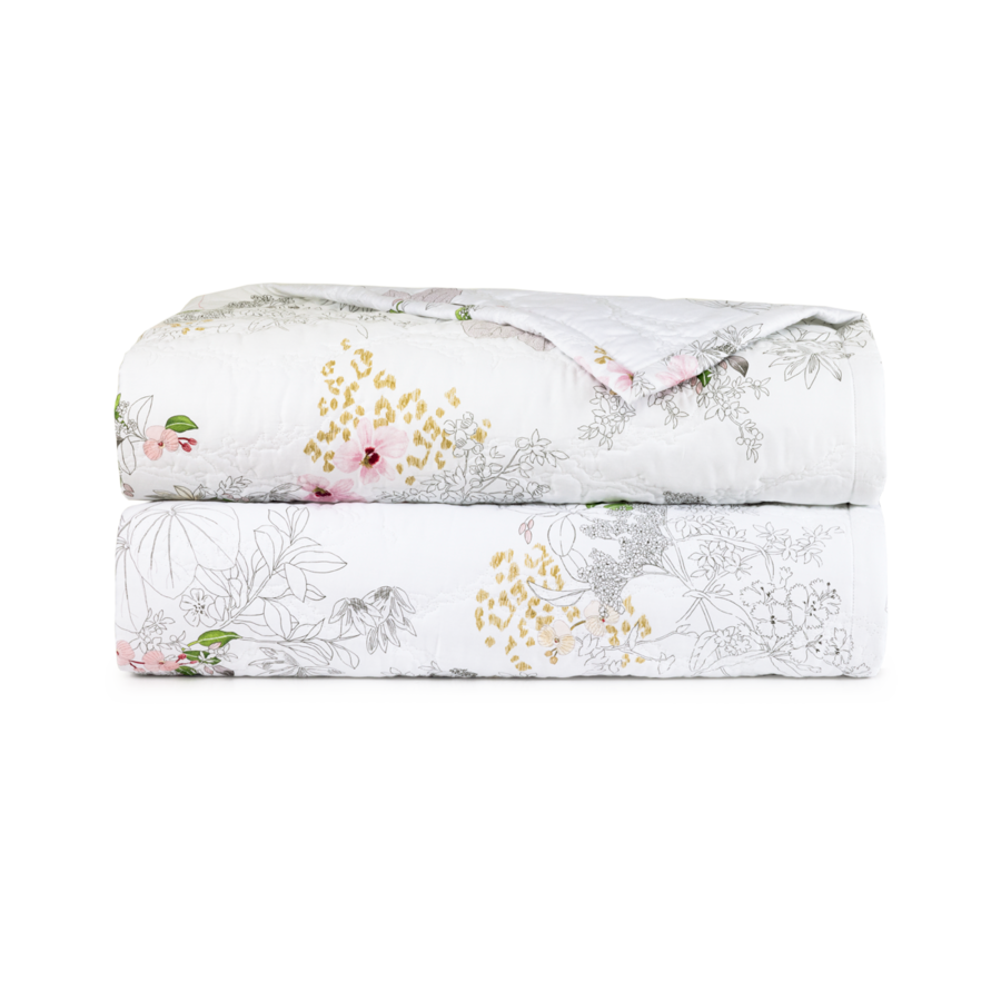 Une courtepointe blanche pliée, ornée d'un léger motif de fleurs roses, de contours gris et de petites formes dorées sur fond blanc.