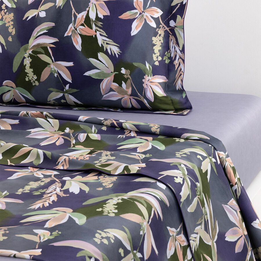 Draps de lit à imprimé botanique de feuilles dans des tons de vert et de beige discrets.