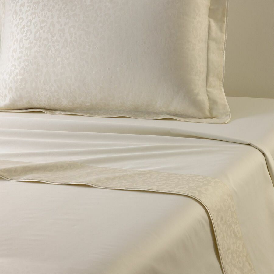 Draps et oreiller couleur crème avec un discret motif animalier.