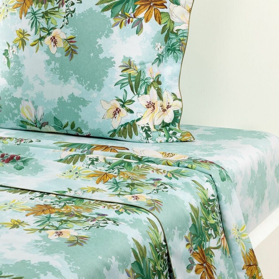 Un lit avec une couette fleurie et des oreillers dessus